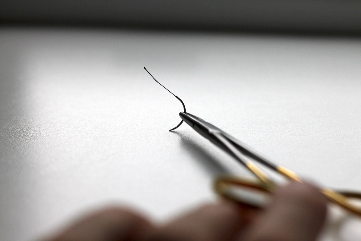 A needle holder holding a curved needle near its tip