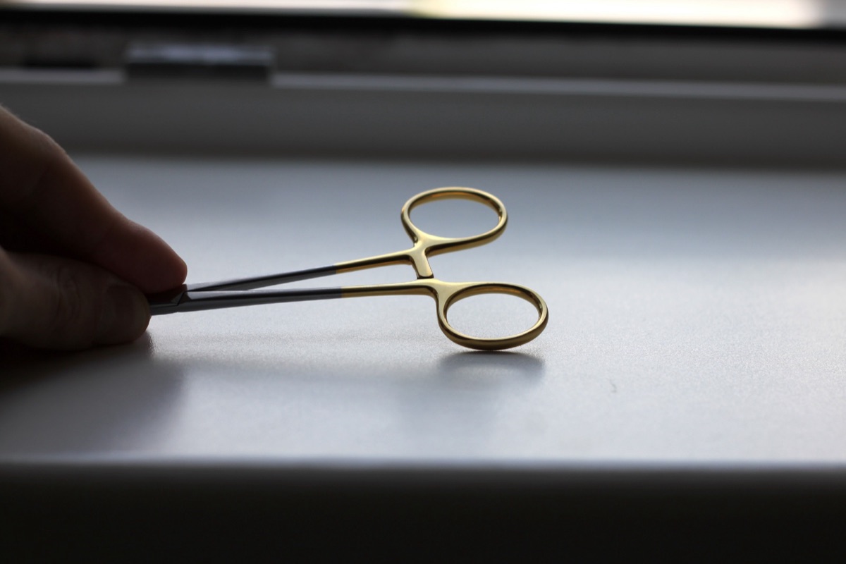 A needle holder resting closed on a work surface
