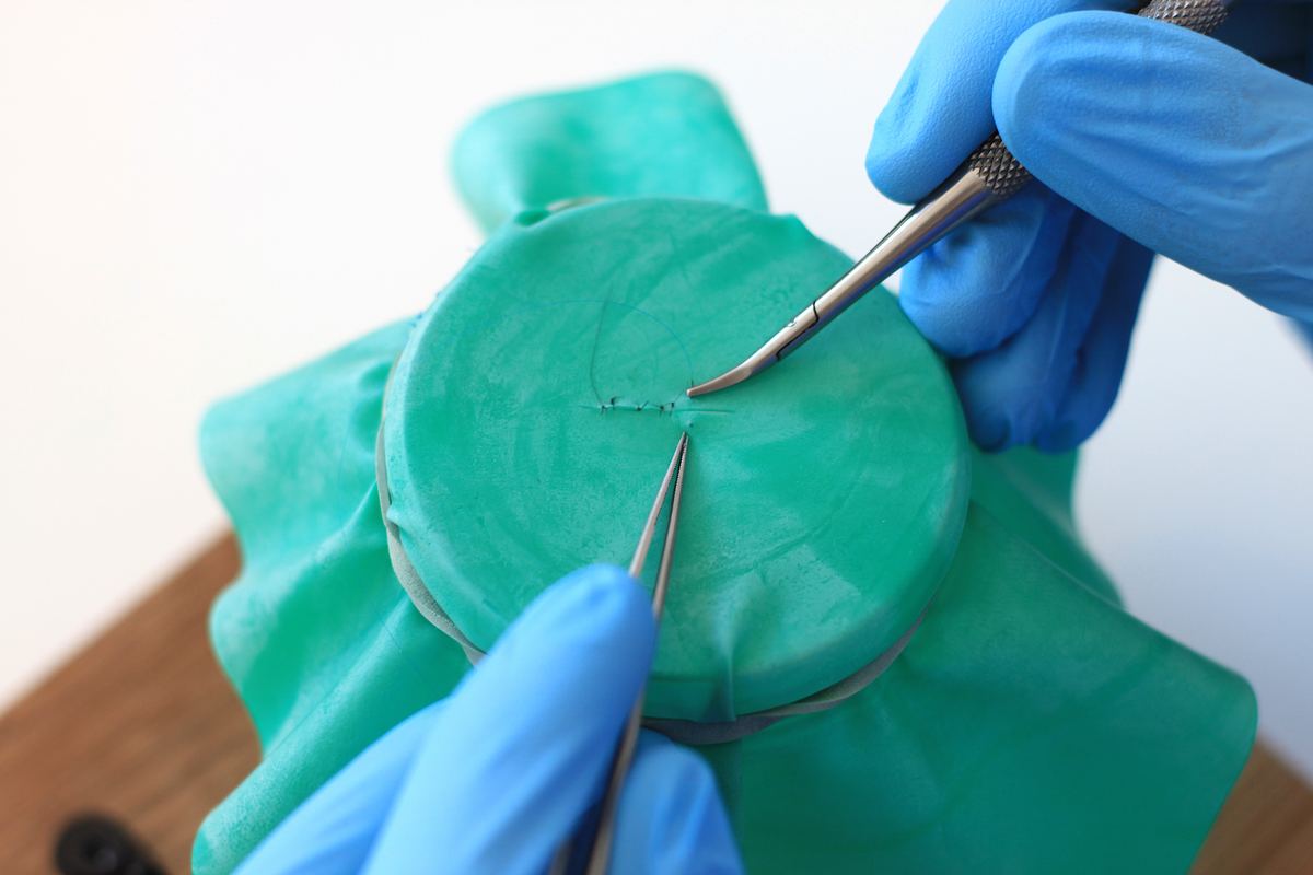Microsurgical suture on a rubber sheet stretched over the cylinder